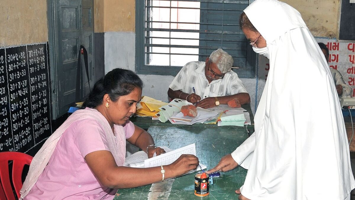 A lady poling officer administering indelible ink to the finger of a Muslim lady voter during the third phase of General Election-2009 at Ahmedabad, Gujarat on April, 30, 2009