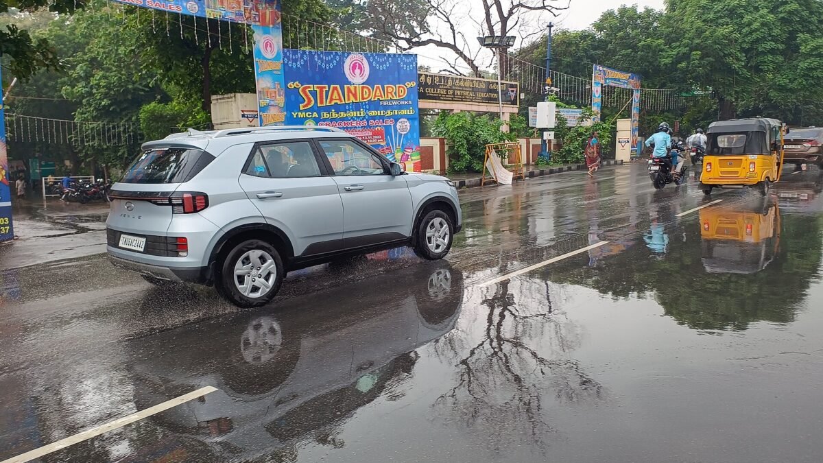 A wet, rain-soaked stretch of Anna Salai in Chennai with puddles on the road