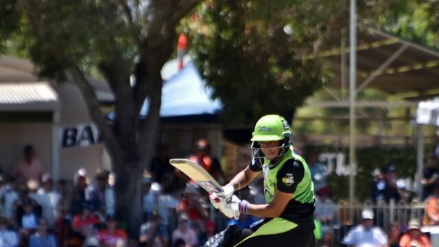Harmanpreet Kaur in a green Sydney Thunder kit playing a shot during a women's cricket match