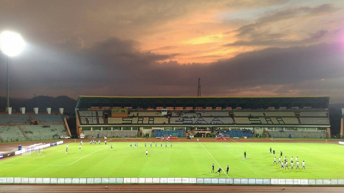 Floodlit football pitch and main stand of the Indira Gandhi Athletic Stadium, Guwahati, at dusk