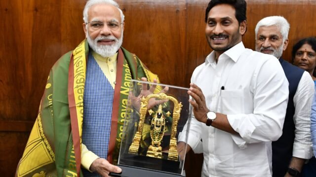 YS Jagan Mohan Reddy in a white shirt standing beside Prime Minister Narendra Modi, who holds a memento