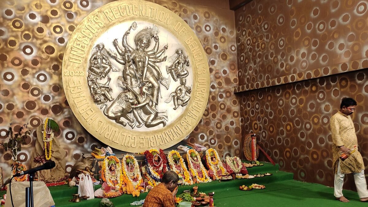 Priests performing Navami puja before a large circular Durga relief at a pandal in Kolkata