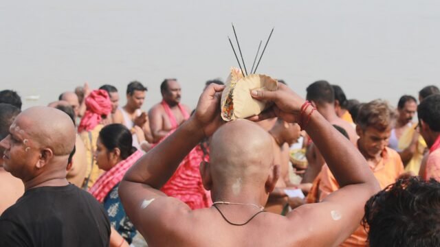 Devotees performing tarpan at a riverbank on Mahalaya