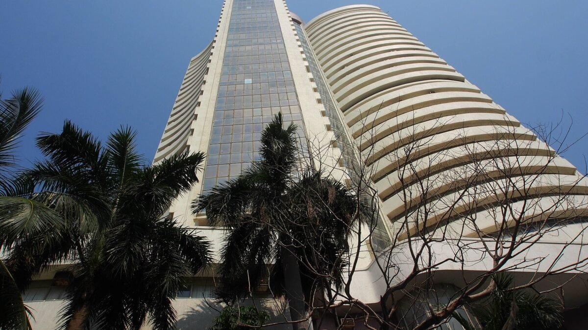 Low-angle view of the BSE tower in Mumbai framed by palm trees against a blue sky